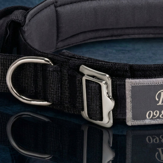 Close-up of heavy-duty metal cobra buckle and stainless steel D-ring on wide black padded tactical dog collar — personalized large breed dog collar
