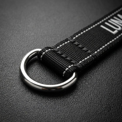 Close-up of stainless steel D-ring on custom embroidered black nylon dog collar with dog name stitched in white